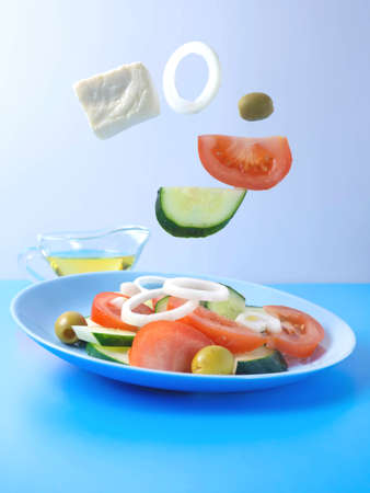 Fresh vegetables fly into the salad on a blue-and-white background. Tomato, cucumber.basil, onion. Creative salad. The concept of healthy food.の写真素材