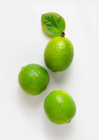 Three delicious limes with a leaf on a white background.の写真素材