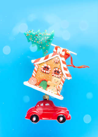 New Years card, poster, creative. A red car is carrying sweets, a New Year gingerbread house and a candy in the form of a Christmas tree on a blue background.の写真素材