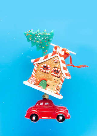 New Year's card, poster, creative. A red car is carrying sweets, a New Year gingerbread house and a candy in the form of a Christmas tree on a blue background.の写真素材