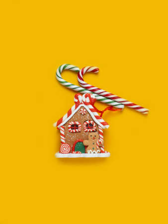 Gingerbread house, red clock, gift, lollipop, candy on a yellow background.の写真素材