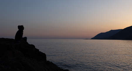 a man sits on a high seashore and watches the sunset, Greece, Crete, Chaniaの写真素材