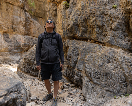 a man stands in a mountain gorge and looks at the rocks, Greece, Crete, Samaria