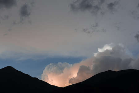 voluminous clouds in the sunset rays in a mountain valleyの写真素材