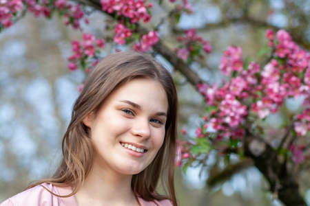 portrait of a young girl in the park against the backdrop of cherry blossomsの写真素材