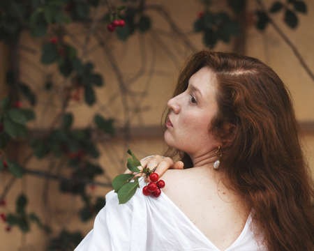 Portrait of a young woman with a sprig of cherry berriesの写真素材