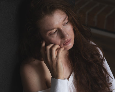 Portrait of a young woman sitting on the floor, against a dark backgroundの写真素材