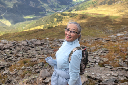 A woman stands on a rocky mountain path and smiles at the camera, Austrian Alpsの写真素材