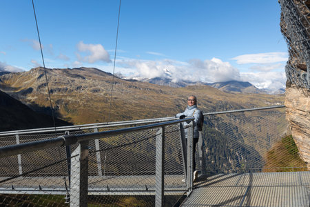 Woman posing on a metal suspension bridge over a mountain precipice, austrian alpsの写真素材