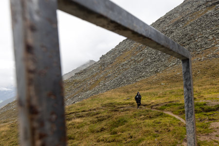 A woman in a rain cape climbs a mountain path, a picture in a metal frame. Austria, Alpsの写真素材