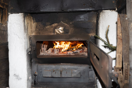 A bright fire burns in an old stove with an open metal door, copy space