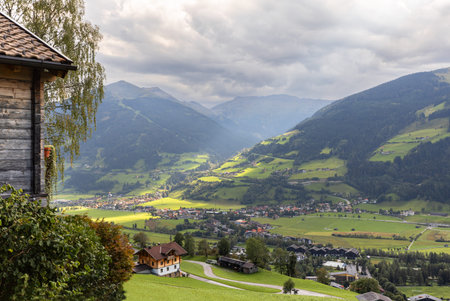 Alpine summer mountain landscape with sun glare in the valley and rural buildings, Salzburg, Austria