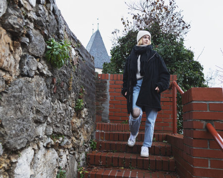 A warmly dressed girl descends a well-groomed brick staircase down from the church.