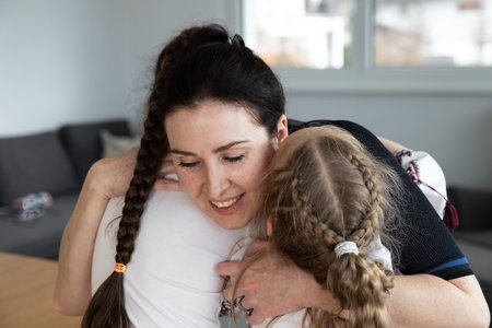 Beautiful happy mother hugs two daughters with long hair