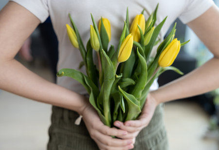 The girl has a gift for women behind her - yellow tulipsの写真素材