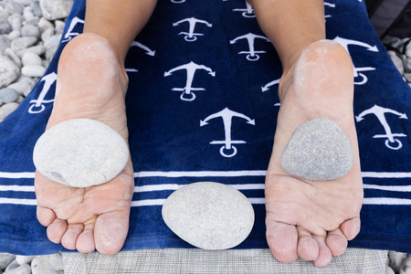 On the feet of a man lying on a sun lounger are round hot stones.の写真素材