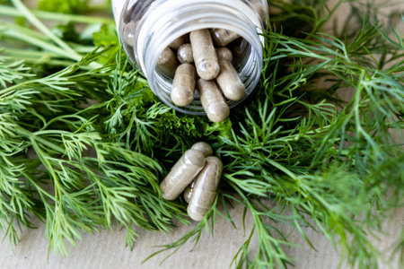 Herbal tablets poured out of the jar on dill branches, a concept of natural additivesの写真素材