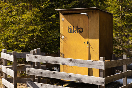 Yellow Wooden toilet with a fence of boards and a funny inscription stands in the forest area among the fir treesの写真素材