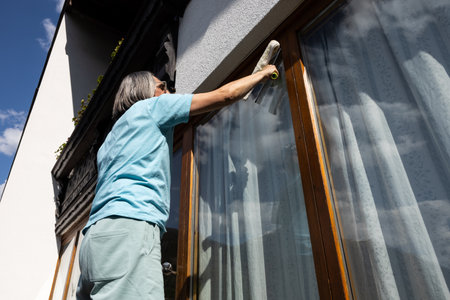 Portrait of an adult man who cleans home windows from the street sideの写真素材