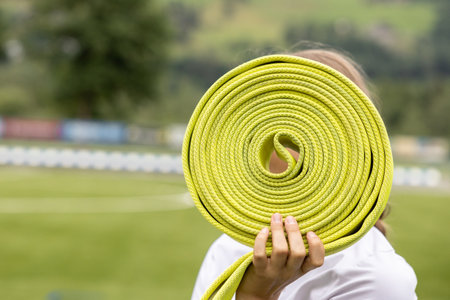 Portrait of a girl covering her face with a rolled-up green fire barrierの写真素材