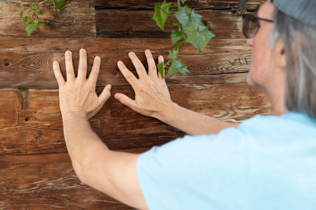 The man put his hands on the old wooden walls of a residential buildingの写真素材