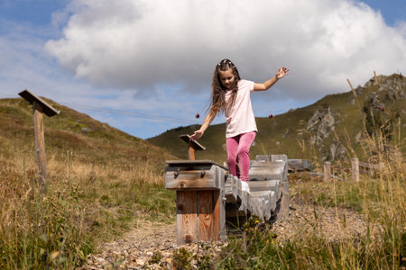 A girl in pink moves on movable logs at a childrens playground in the Alps, Austriaの写真素材
