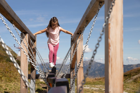 A girl moves carefully on a suspended wooden exercise machine for balance training in the Austrian Alpsの写真素材