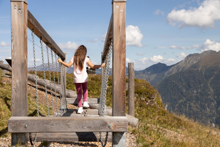 Long-haired girl walking on movable logs on playground in mountains, Austria, Alpsの写真素材