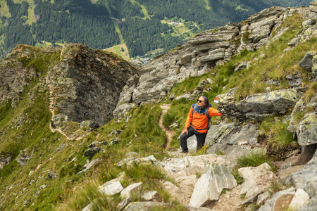Man stopped on climb on rocky trail and resting on rocky ridge background, Austriaの写真素材