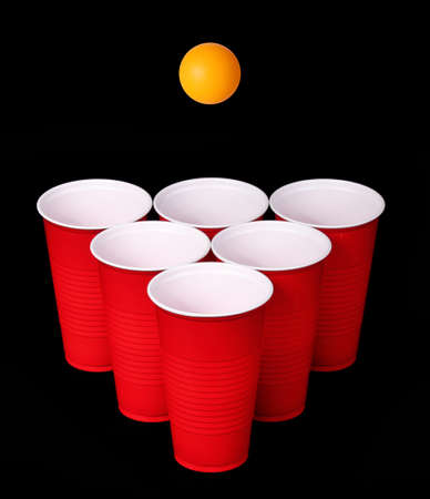 Beer pong  Red plastic cups and orange table tennis ball over black background  Closeupの写真素材