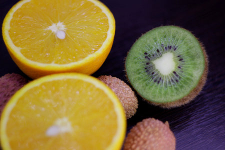 still life of citrus, juicy kiwi and orange in the cut and Litchi chinensis on a dark backgroundの写真素材