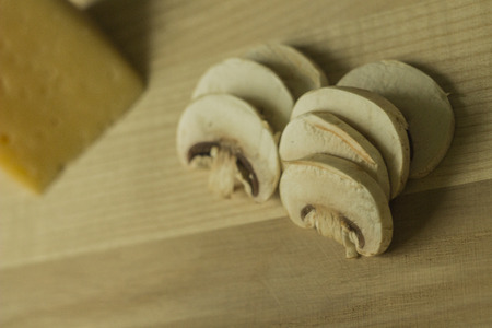 sliced ââchampignons with cheese on a kitchen board on wooden backgroundの写真素材