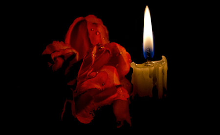 Photo of a red rose and a candle with black backgroundの写真素材