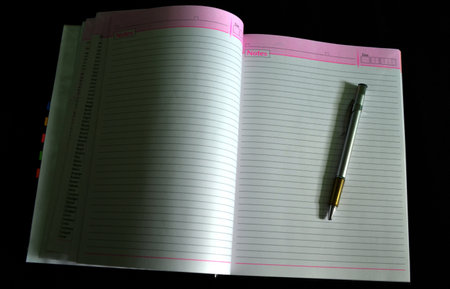 Notebook and pen on a black background, close-up.の写真素材