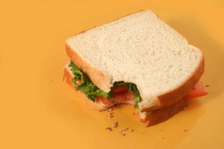 eating a ham sandwich with tomatoes and lettuceの写真素材