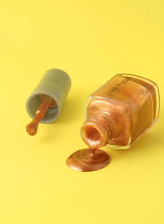 metallic gold nailpolish spilling from the bottleの写真素材