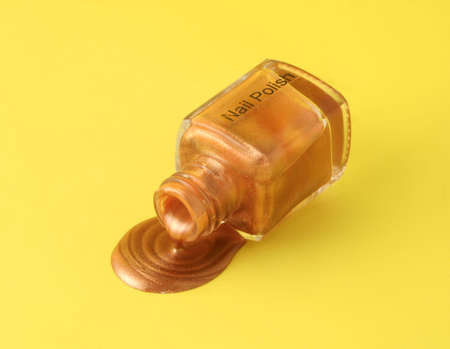 metallic gold nailpolish spilling from the bottleの写真素材