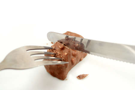 cutting a small chunk of chocolate with knife and forkの写真素材