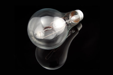 an electrical lightbulb reflected on black background