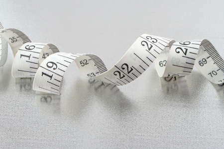 curled up measuring tape on silver backgroundの写真素材