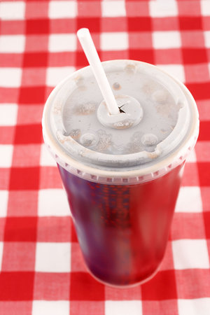 a soft drink in a takeout paper cup with lid and straw