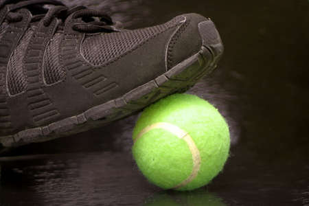 black sports sneaker on green tennis ball の写真素材