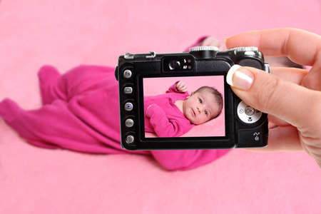 woman takes snapshot of a small one week old newborn baby girl on a pink background の写真素材