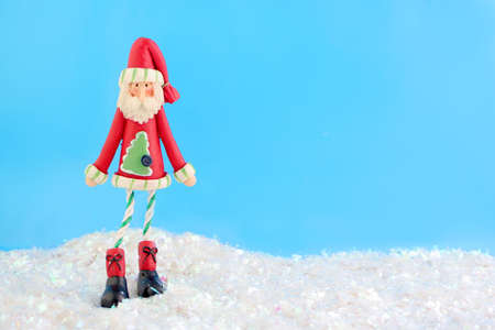 slim santa claus christmas decoration on fake snow and blue backgroundの写真素材