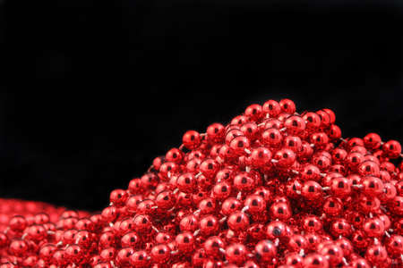 closeup of cluster of red stringed sparkling christmas beads with a black backgroundの写真素材
