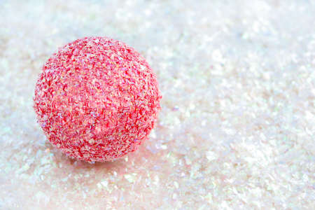 pink sparkly christmas decoration ball on white glitter great for backgrounds, name tags or greeting cardの写真素材
