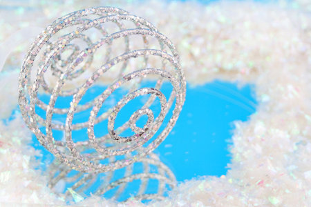  sparkly swirly  christmas ball with reflection on blue surrounded by fake snowの写真素材
