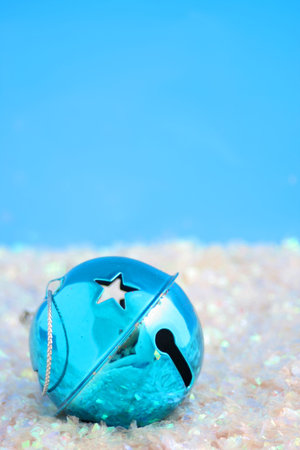blue christmas bell  surrounded by fake snow with blue backgroundの写真素材