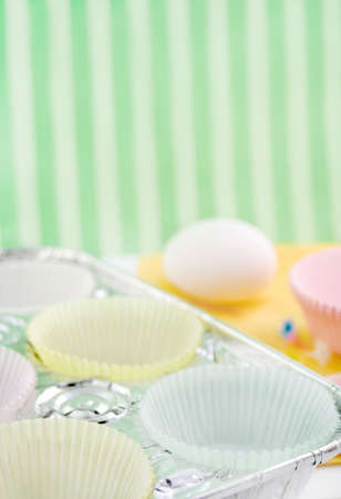cupcake paper cups in baking pan with egg in the background, shallow depth of fieldの写真素材