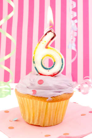 birthday cupcake with pink frosting and and decorative background celebrating child's sixth anniversaryの写真素材